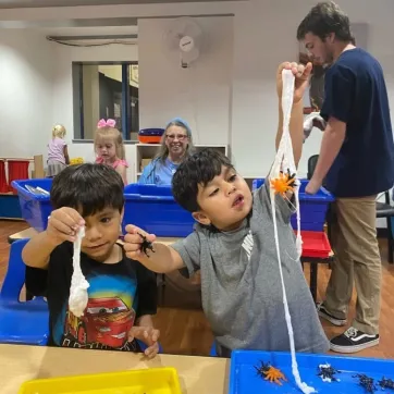 Two boys playing with stringy stuff